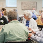 A man looks at a woman while seated at a table with two other men